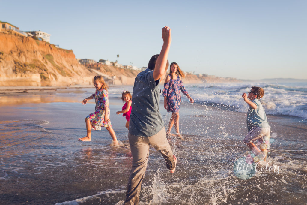 Group of brothers and sisters playing on the beach splashing water