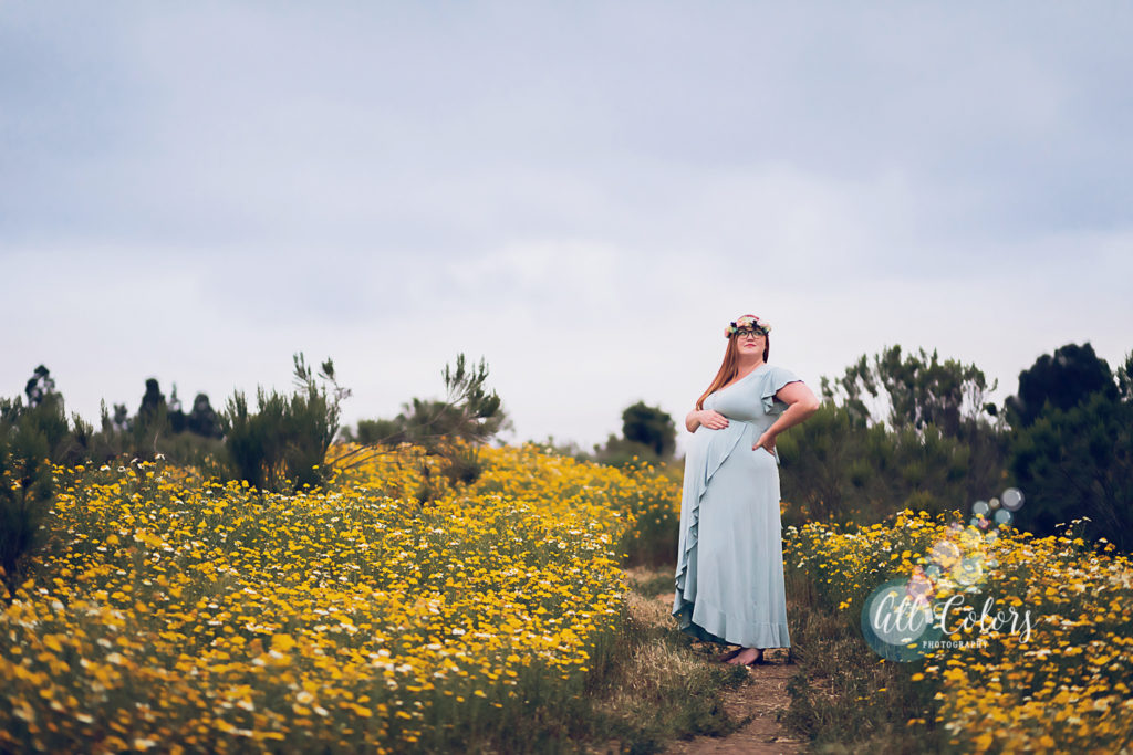 a trail with yellow wildflowers and an expecting woman with a blue dress