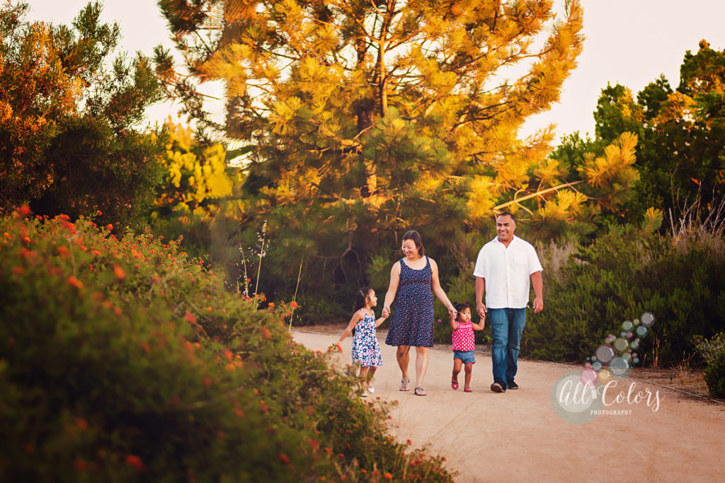 Family of four walking on a path with orange flowers.