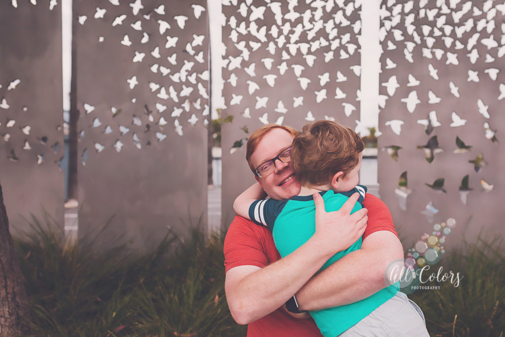 Father hugging son in front of wall of birds.