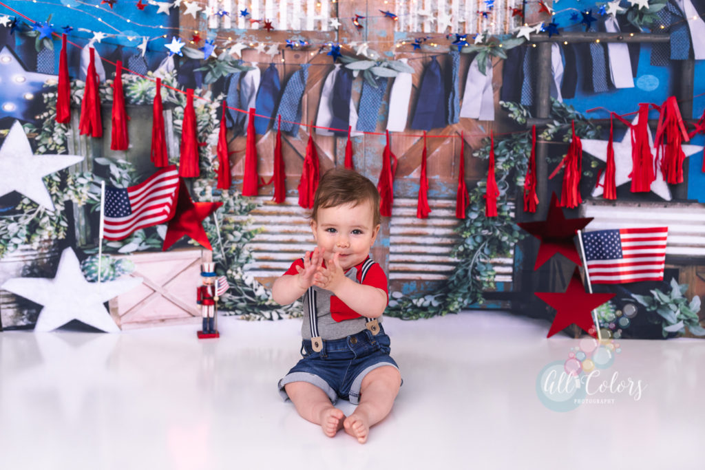 Baby boy clapping in front of 4th of July decorations.