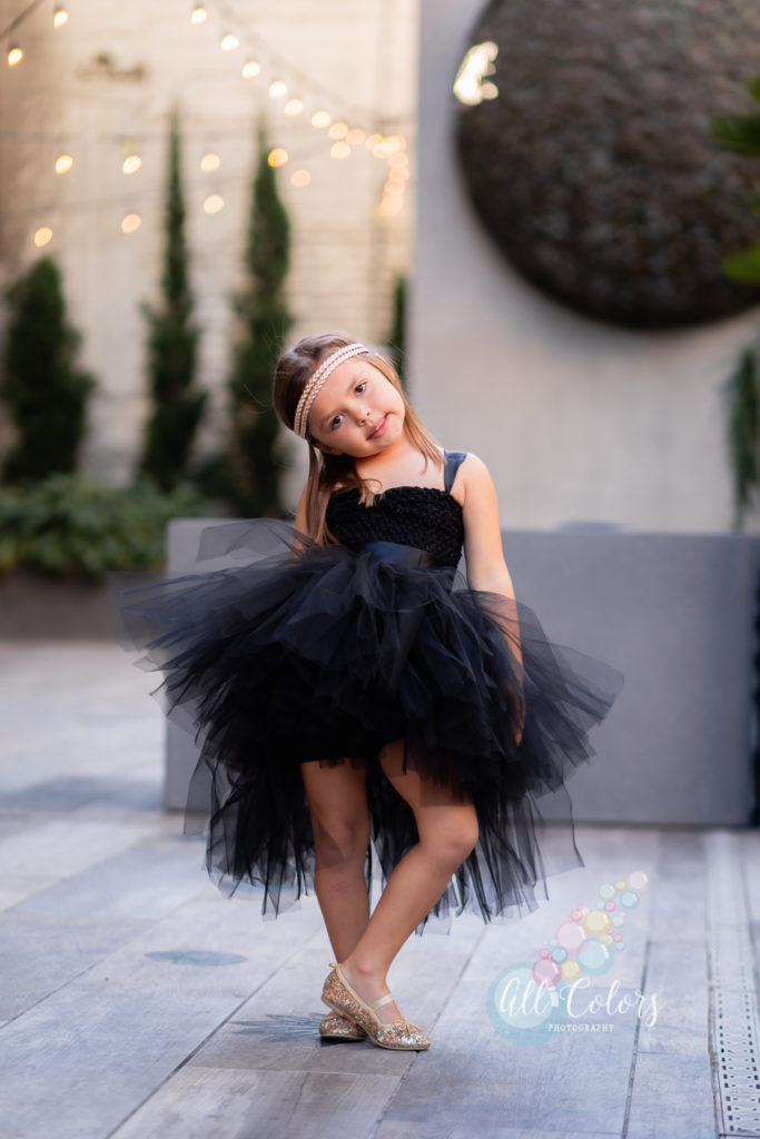 Little girl dressed up in black posing like a model.