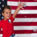 boy throwing glitter in front of an american flag