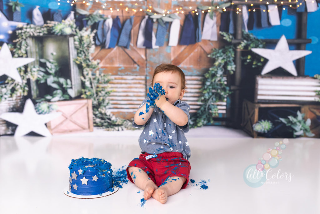baby boy making a mess with a blue cake during a cake smash session in San Diego
