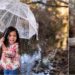 Little girl playing on a water stream with umbrella