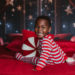 Smiling boy sitting on a bed with a Christmas set up.