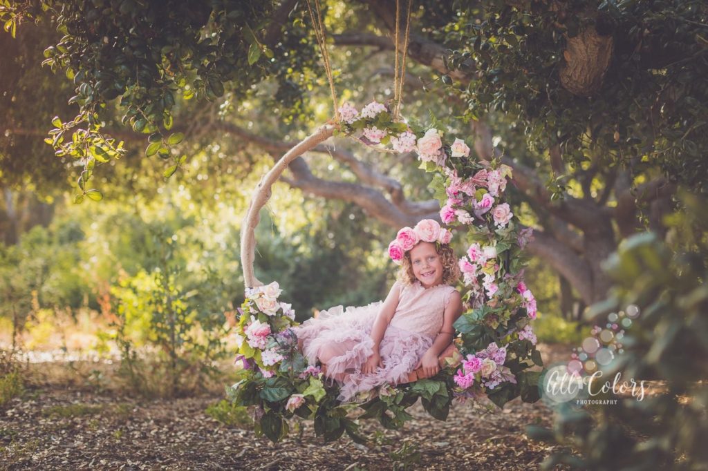 whimsical image of a girl sitting on a flower swing.