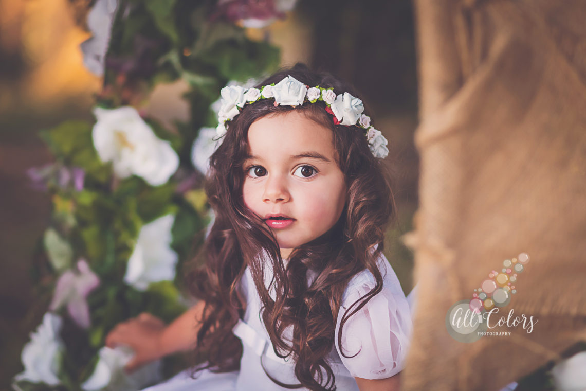 little girl with a flower crown sitting on a flower swing