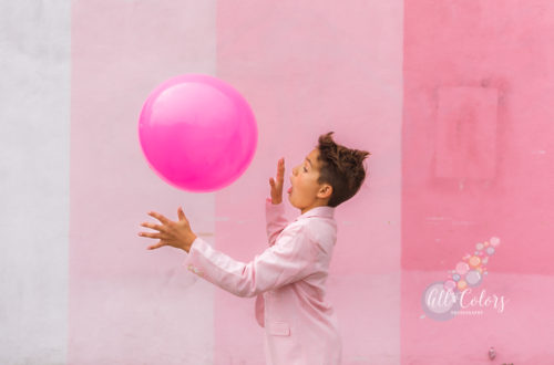 boy wearing a pink suit throwing a pink ball in the air